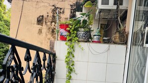 A balcony with a tiled floor, a black wrought iron railing, and potted plants. - BluO Modern Studio - Defence Colony Market (Delhi)