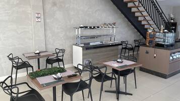 Un comedor moderno con una isla central, sillas negras y una escalera de escalones de madera.