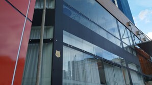 Un edificio moderno con una fachada llamativa de color rojo y azul, grandes ventanales y un logotipo visible.