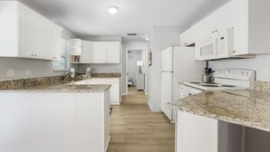 A modern kitchen with white cabinetry, granite countertops, a central island, and a built-in oven. - 2-Bedroom Condo with Waterview Balcony - Tarpon - Welcome to our stunning two-bedroom condo room with a balcony! (Matlacha)