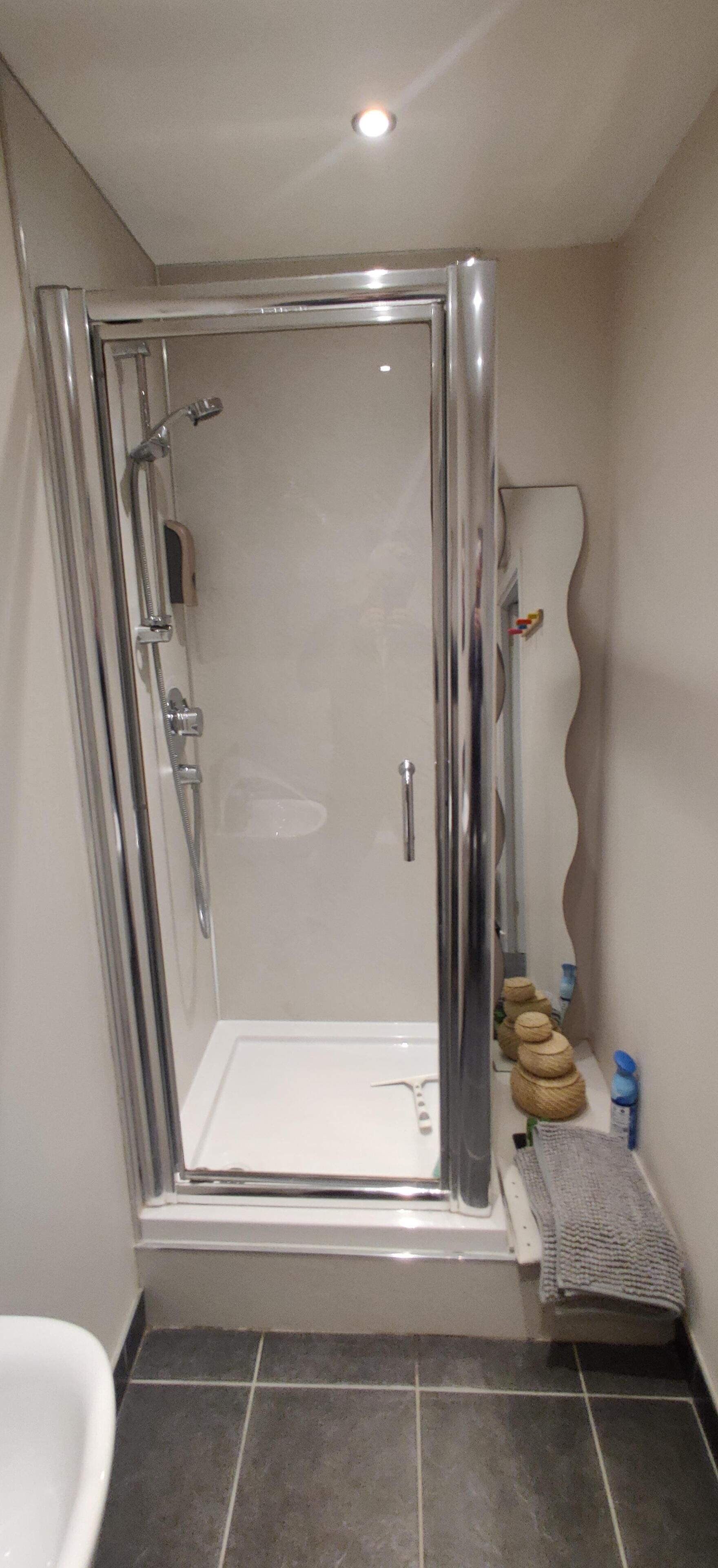 A modern bathroom with a glass-enclosed shower, a white bathtub, and a tiled floor.
