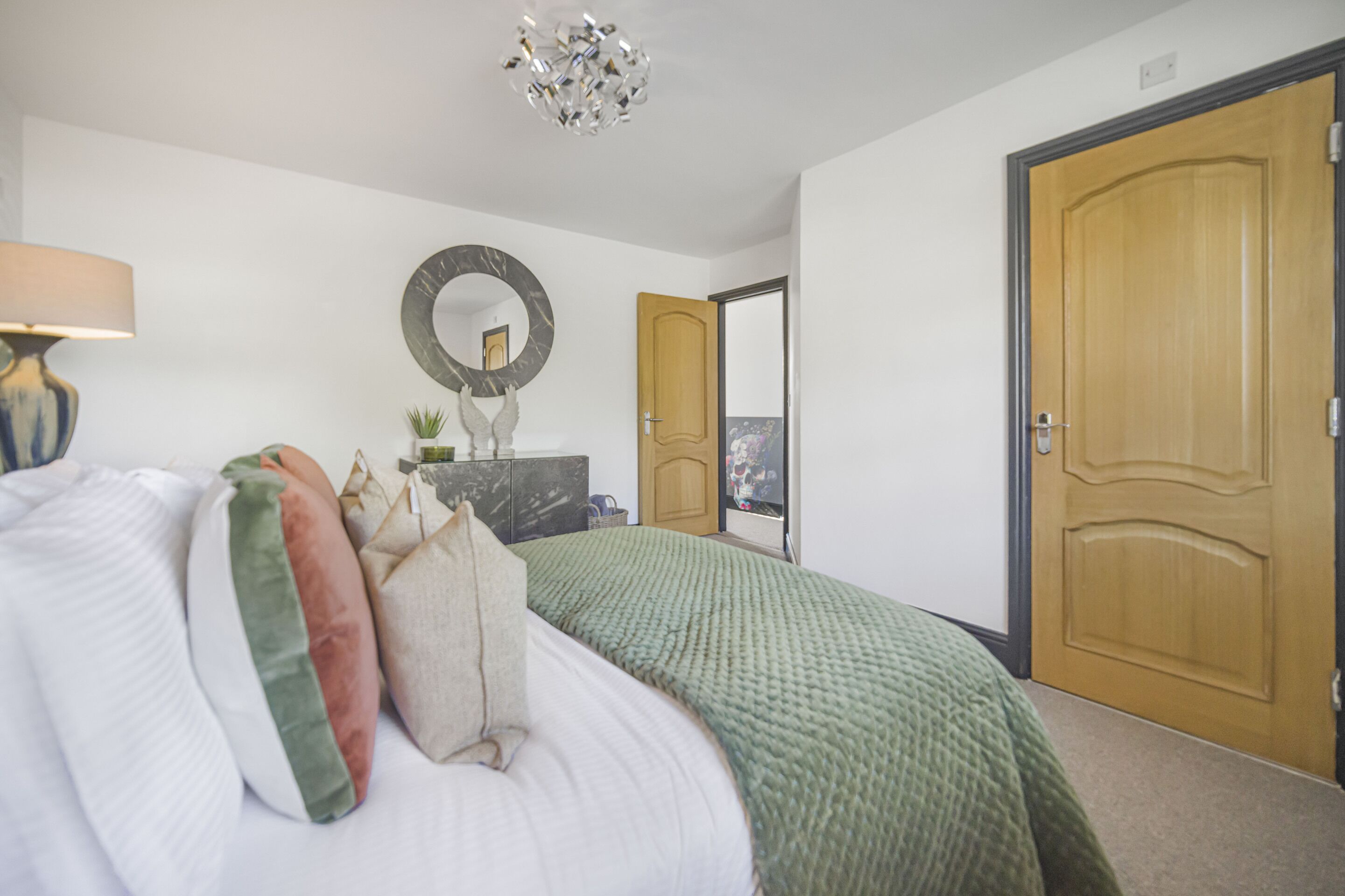 A bedroom with a bed, a dresser, a mirror, and a door.