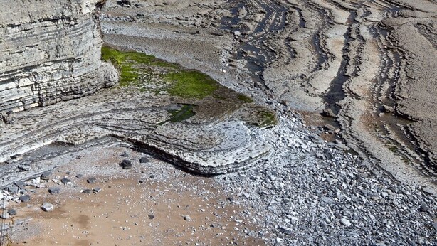 A coastal landscape with layered cliffs and a beach. - Coach House (Bridgend)