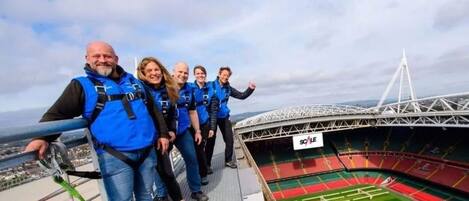 Eine Gruppe von Menschen auf einer Stadionpromenade mit Blick auf das Stadioninnere und eine Brücke im Hintergrund.
