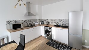 A compact kitchen with a microwave, washing machine, and refrigerator. - Les Nuits Bonneuilloises Le Henson (Breteuil)