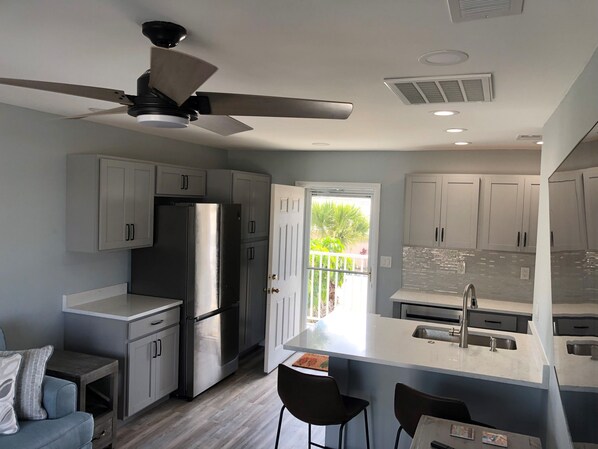 Una cocina moderna con una isla central, electrodomésticos de acero inoxidable y un ventilador de techo.