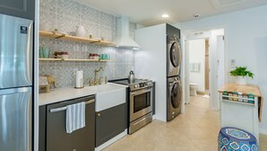A modern kitchen with stainless steel appliances, a patterned backsplash, and a small dining area with a table and chairs. - Coastal Getaway minutes from Siesta Key, America’s #1 Beach (Sarasota)