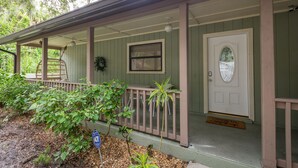 A green wooden porch with a white door, a small window, and a doormat. - Coastal Getaway minutes from Siesta Key, America’s #1 Beach (Sarasota)