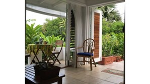 En overdækket terrasse med et bord, stole og plantekrukker.