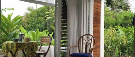 A covered patio with a table, chairs, and potted plants.