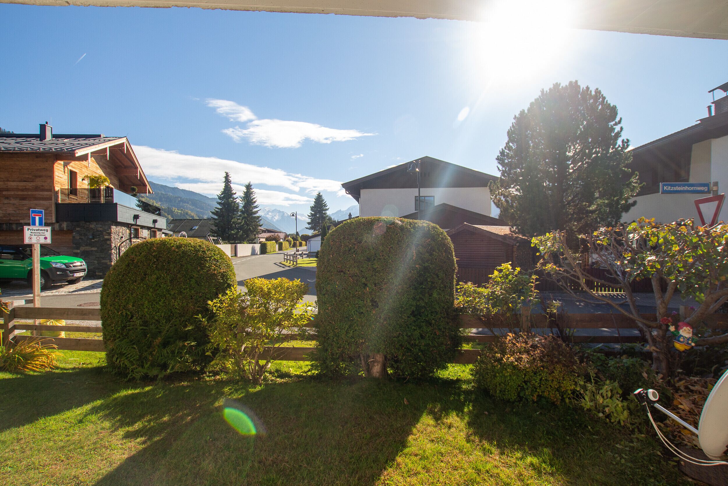 A residential area with a wooden house, a modern building, and a mountain backdrop.
