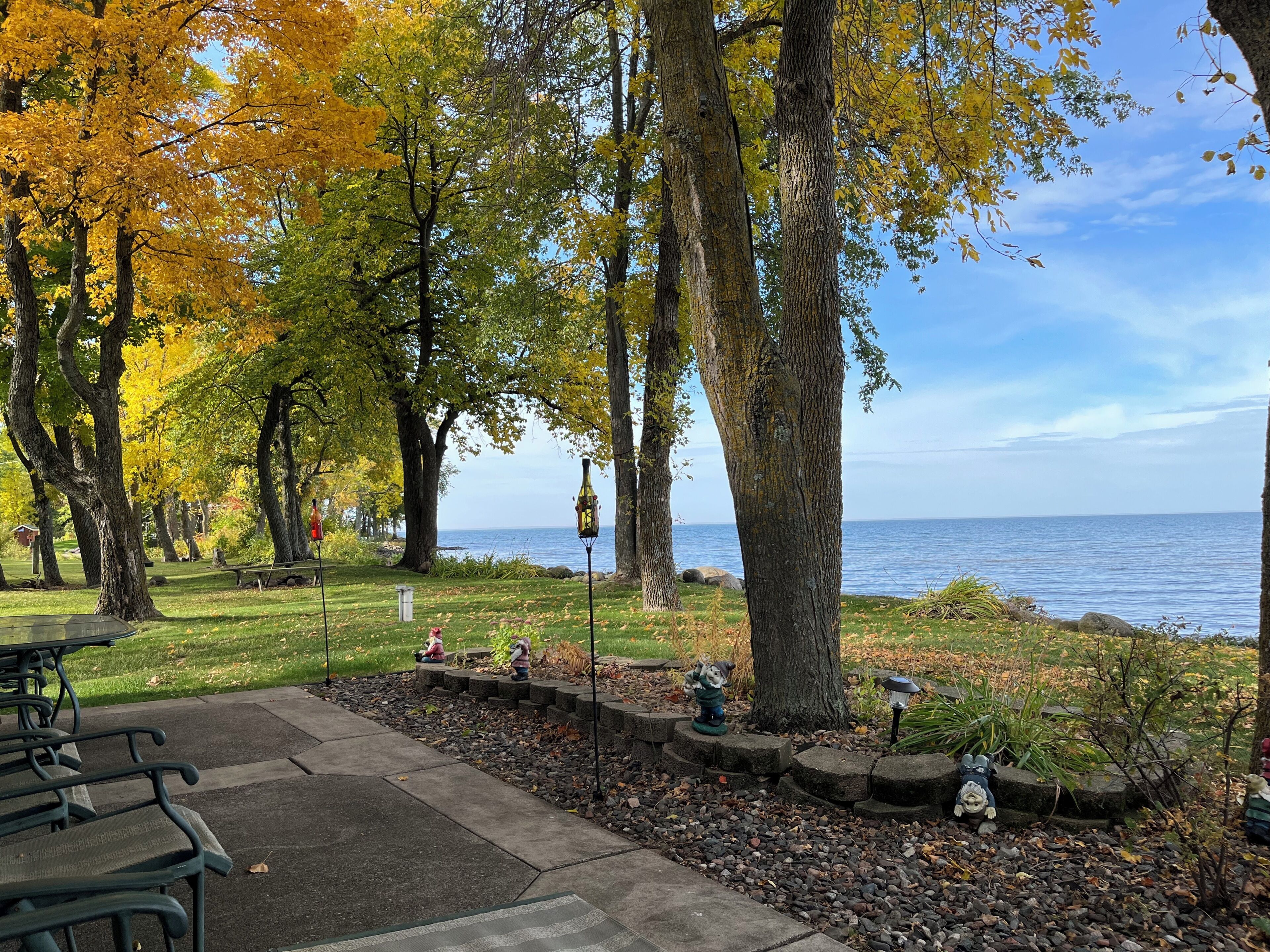 A park with picnic tables, a statue, and a view of the water.