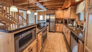 A modern kitchen with wooden cabinets, stainless steel appliances, and a granite countertop. - Lake Access, Dock, Hot Tub, Fire Pit , Free Golf + Pickle Ball (Swanton)
