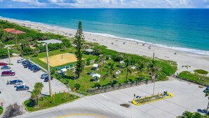 Vista a la playa con estacionamiento, sombrillas y una vista despejada del océano.