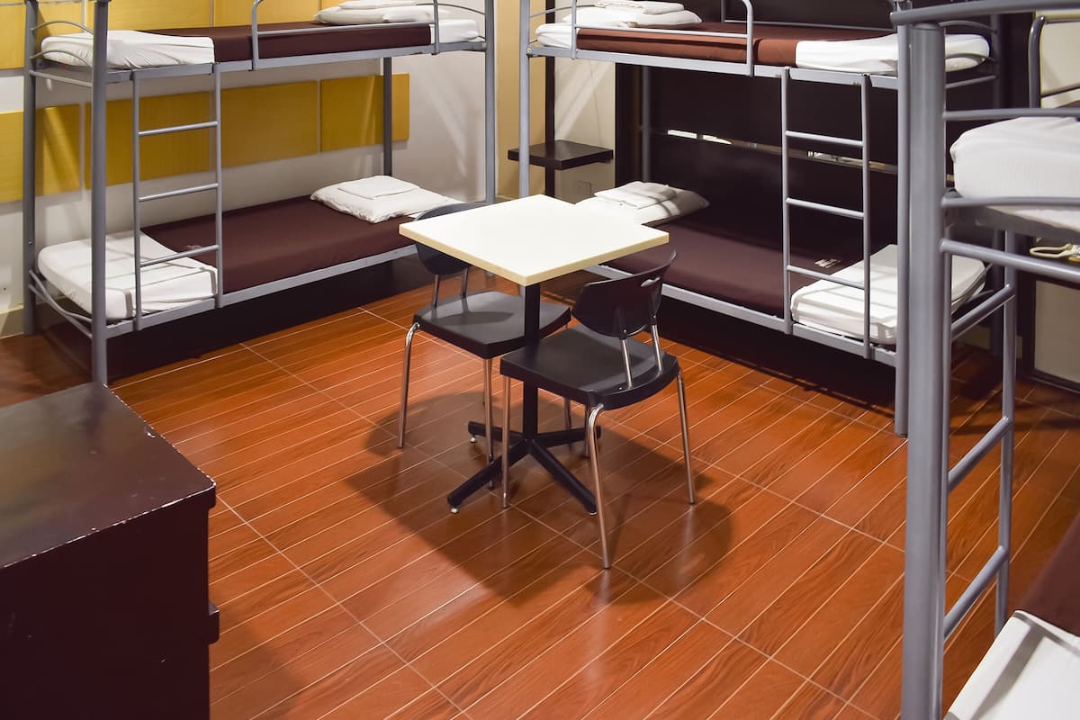 A bunk room with metal bunk beds, a small table, and a chair.