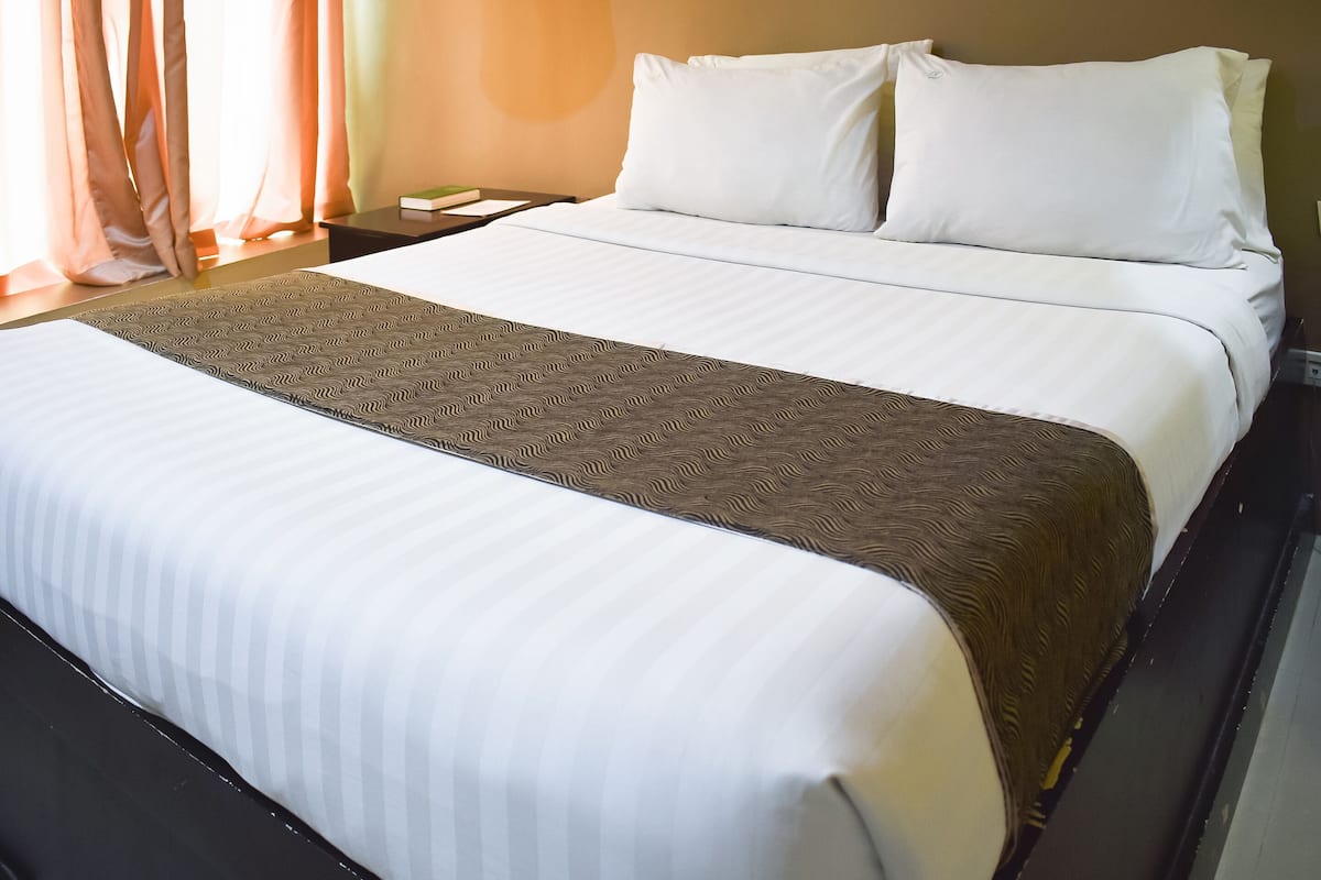 A neatly made bed with white linens and a patterned throw blanket.