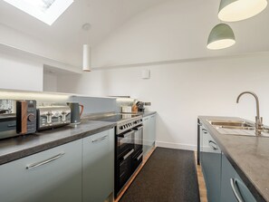 A modern kitchen with a built-in oven, a sink, and a countertop with a coffee maker. - This striking home is ideally located between the beach and the hills. (Arthog)