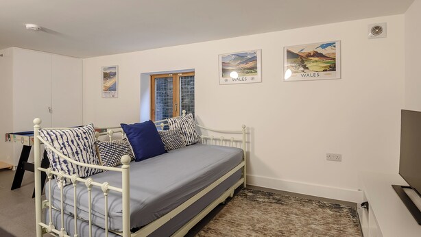 A bedroom with a single bed, a window, and two wall-mounted pictures of Wales. - This striking home is ideally located between the beach and the hills. (Arthog)