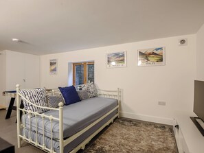 A bedroom with a single bed, a window, and two wall-mounted pictures of Wales. - This striking home is ideally located between the beach and the hills. (Arthog)