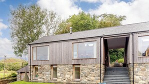 A modern two-story house with a stone facade and large windows. - This striking home is ideally located between the beach and the hills. (Arthog)