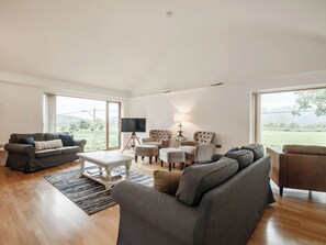 A spacious living room with a large window, a flat-screen TV, and a comfortable seating area.