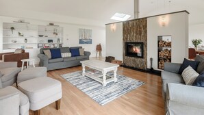 A modern living room with a fireplace, wooden flooring, and a white ceiling. - This striking home is ideally located between the beach and the hills. (Arthog)