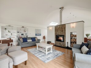 Un salon moderne avec une cheminée, un plancher en bois et un plafond blanc.