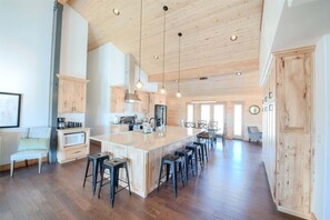 A spacious kitchen with a large island, wooden cabinets, and bar stools.
