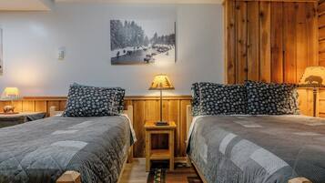 Een kamer met twee bedden, een houten kast, een lamp en een schilderij aan de muur.