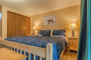 Ein Schlafzimmer mit einem hölzernen Bett, zwei Nachttischlampen, einem Nachttisch aus Holz und einem großen Holzschrank.