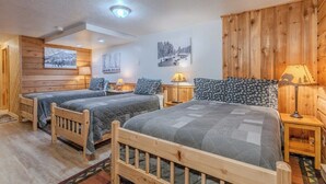 A room with two wooden beds, a wooden wall panel, and a ceiling light. - The Trailhead Townhouse (West Yellowstone)