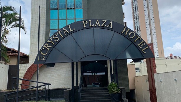 La entrada del Hotel Crystal Plaza, con un diseño arquitectónico moderno, presenta un amplio arco de entrada y una escalera que conduce al vestíbulo.