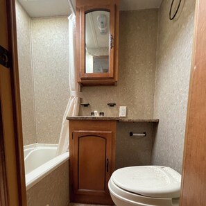 Een bad/douchecombinatie, een haardroger, handdoeken, zeep