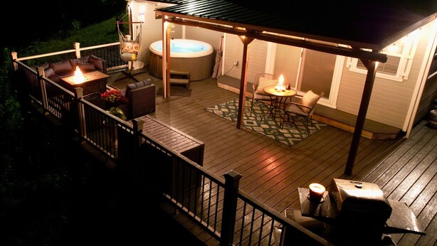 Een terras met buitenmeubilair, een jacuzzi en een barbecueplek.