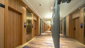A long, narrow hotel corridor with wooden doors on both sides, a patterned carpet, and a modern ceiling design. - Greentree Eastern Li Lake Yuantouzhu Scenic Area Hotel (Wuxi)