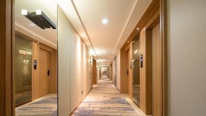 A hotel corridor with wooden doors, a patterned carpet, and a long hallway. - Greentree Eastern Li Lake Yuantouzhu Scenic Area Hotel (Wuxi)