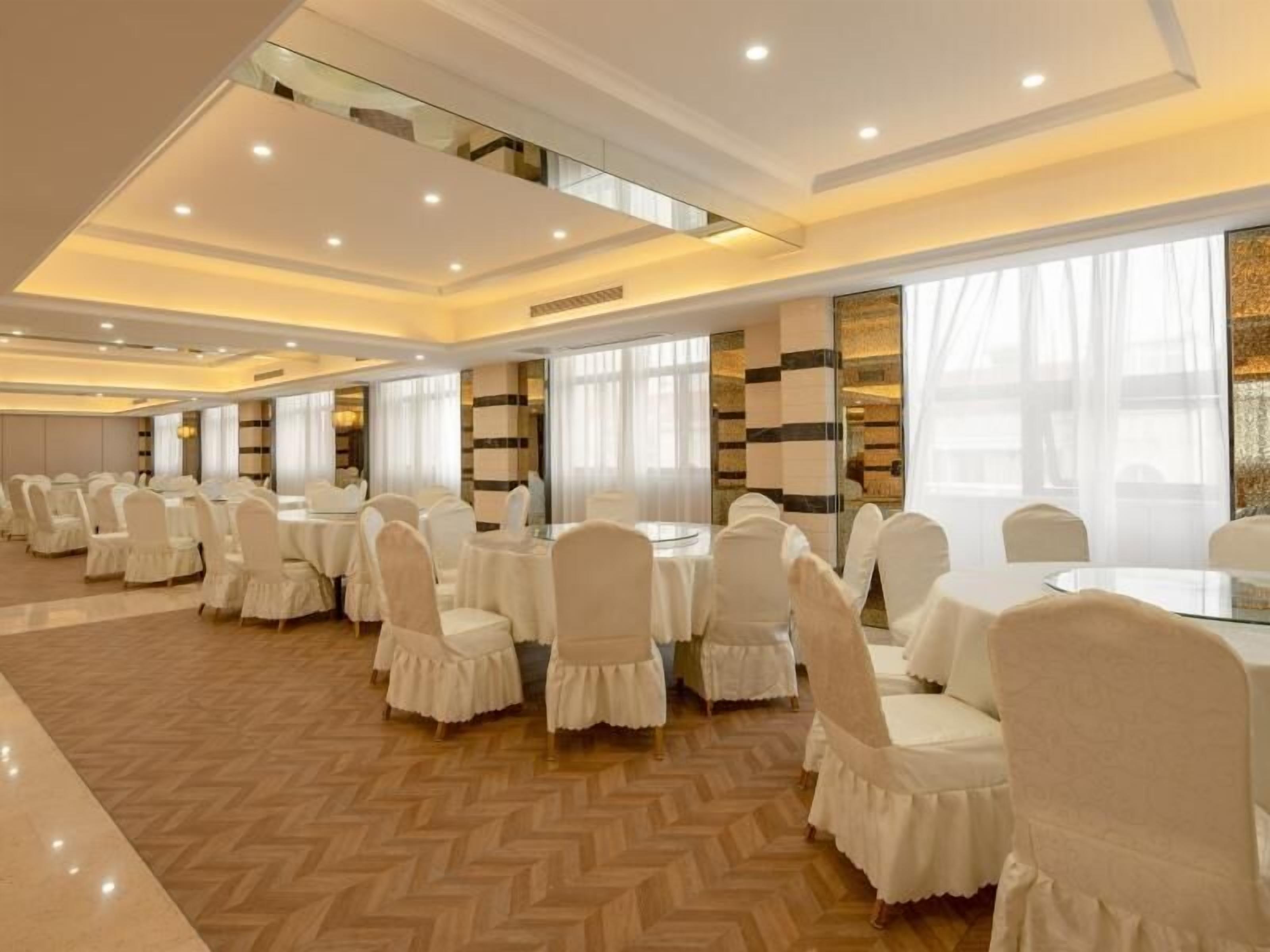 A conference room with round tables and white chairs, large windows, and a herringbone patterned floor.