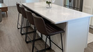 A modern kitchen with a large island, bar stools, pendant lights, a refrigerator, and a flat-screen TV. - Beautiful 2 Bedroom Home In SLC with Private Hot Tub!  (Salt Lake City)