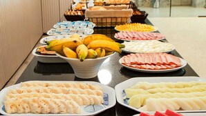 Una mesa de buffet con diversos alimentos, entre ellos frutas, quesos y carnes.