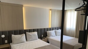 Habitación de hotel con dos camas, una mesita de noche y un espejo.