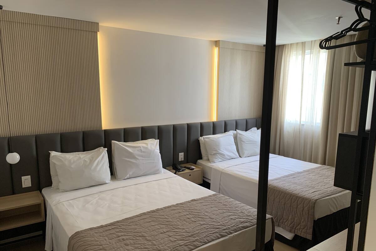 Habitación de hotel con dos camas, una mesita de noche y un espejo.