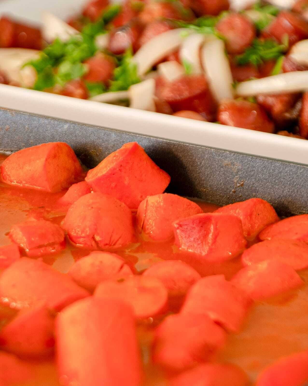 A close-up of a dish with diced carrots and onions in a broth.