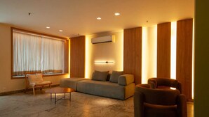 Una sala de estar moderna con un sofá, sillas, una mesita de centro y un ventanal con cortinas.