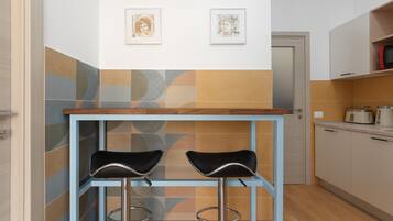 A modern kitchen with two bar stools, a wooden countertop, and a microwave on the countertop.