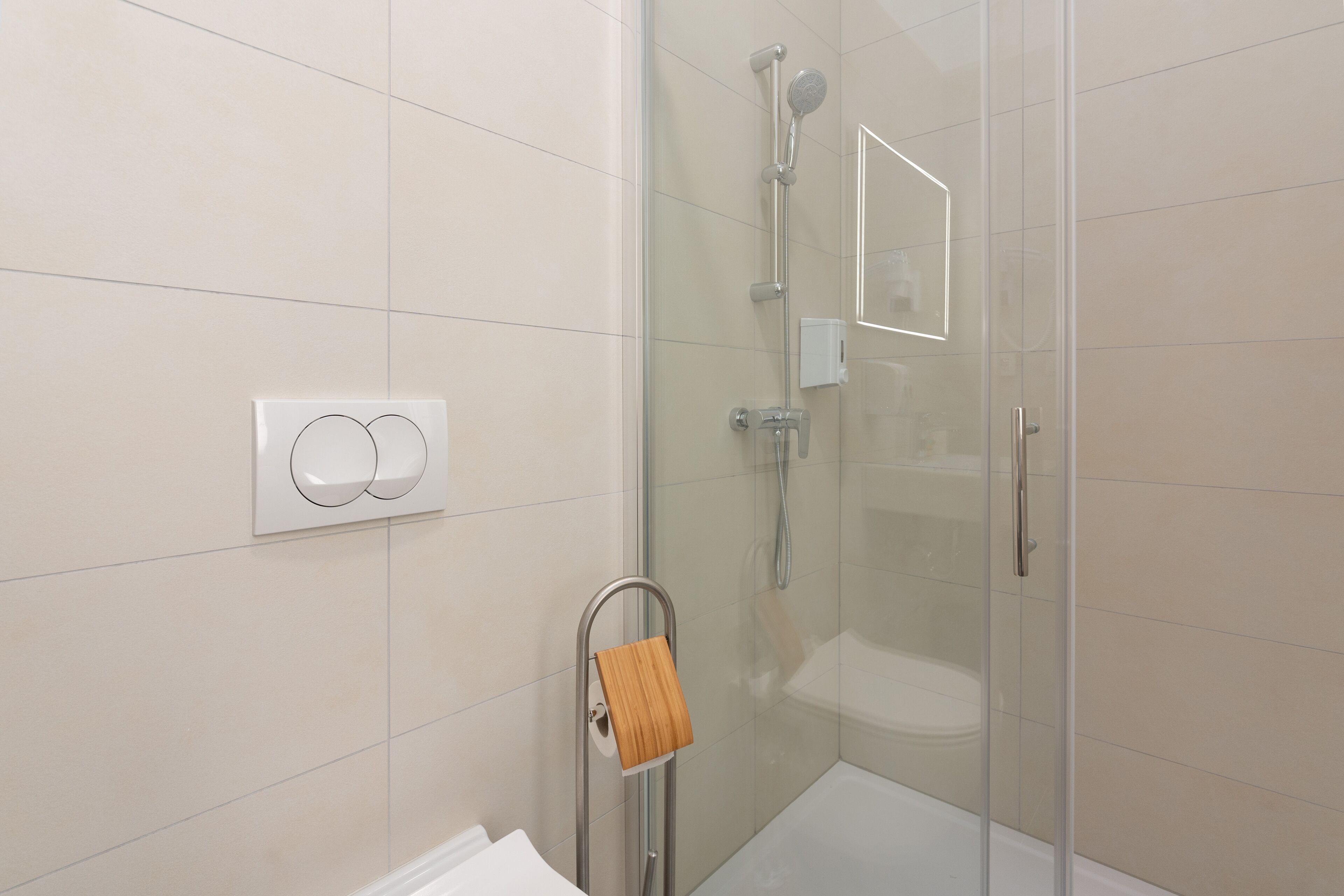 Une salle de bain moderne avec une douche à parois de verre, des toilettes et un porte-serviettes en bois.