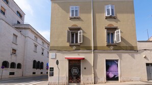 A building with a beige facade, white shutters, and a red awning. - Polesana Rooms (Pula)