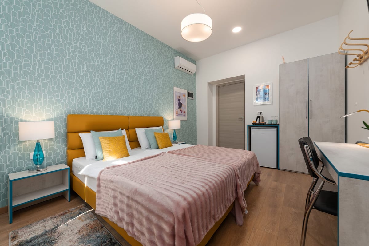 A modern bedroom with a bed, bedside tables, a desk, and a wardrobe.