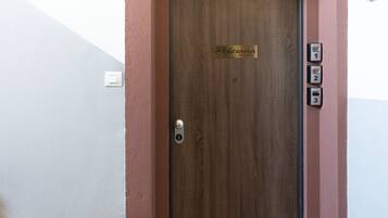 Une porte en bois avec une enseigne indiquant « Polesana Rooms » et trois boutons numérotés sur le côté droit.