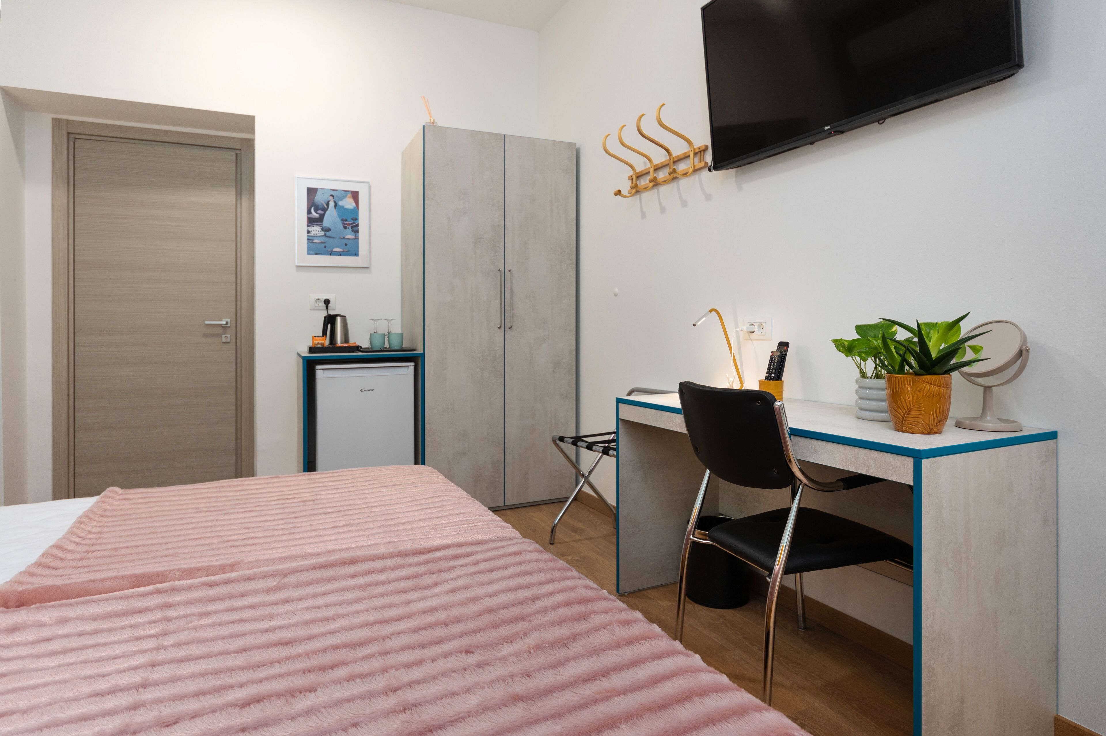 A bedroom with a bed, a desk, a chair, a television, and a wardrobe.