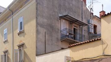 Um edifício com terraço indicado, janelas com persianas e antena parabólica.
